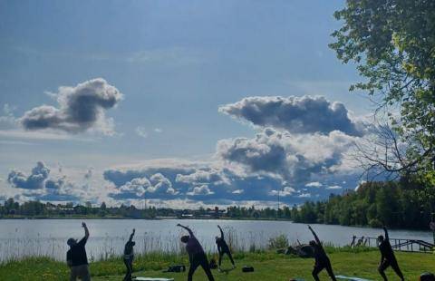 Ihmisiä jumppaamassa meren rannalla auringon paistaessa.