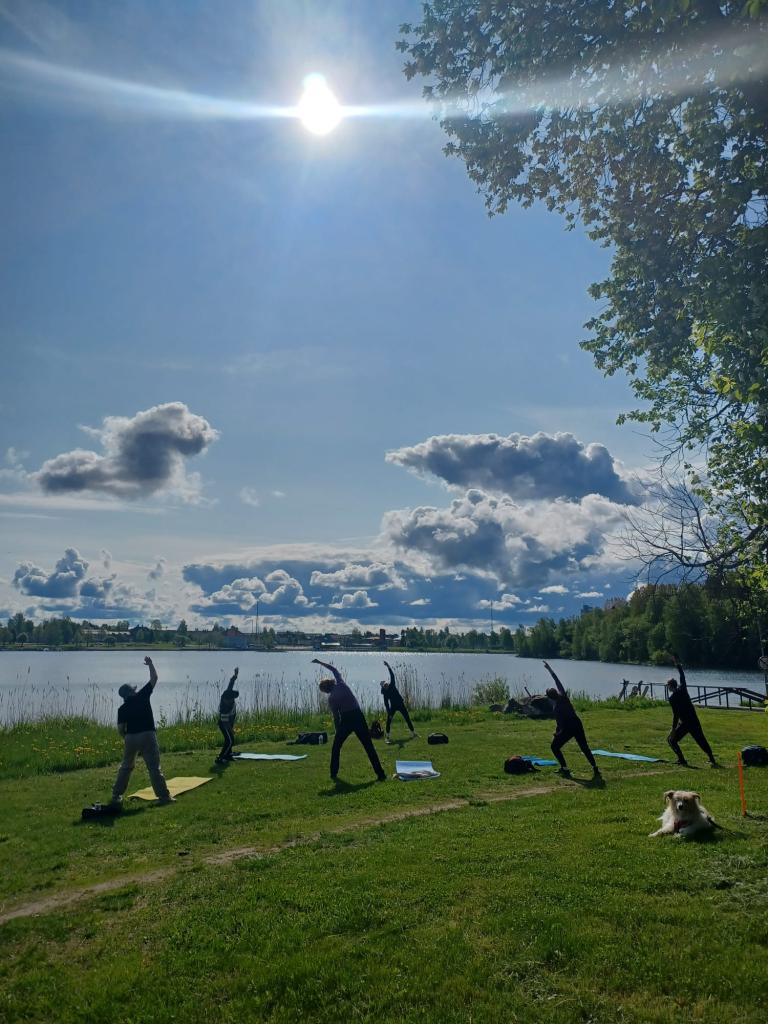 Kesäkuun biitsijumpan maisemat. Ihmisiä jumppaamassa meren rannalla auringon paistaessa.